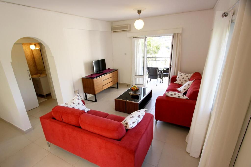 a living room with two red couches and a television at The Love Nest in Pissouri