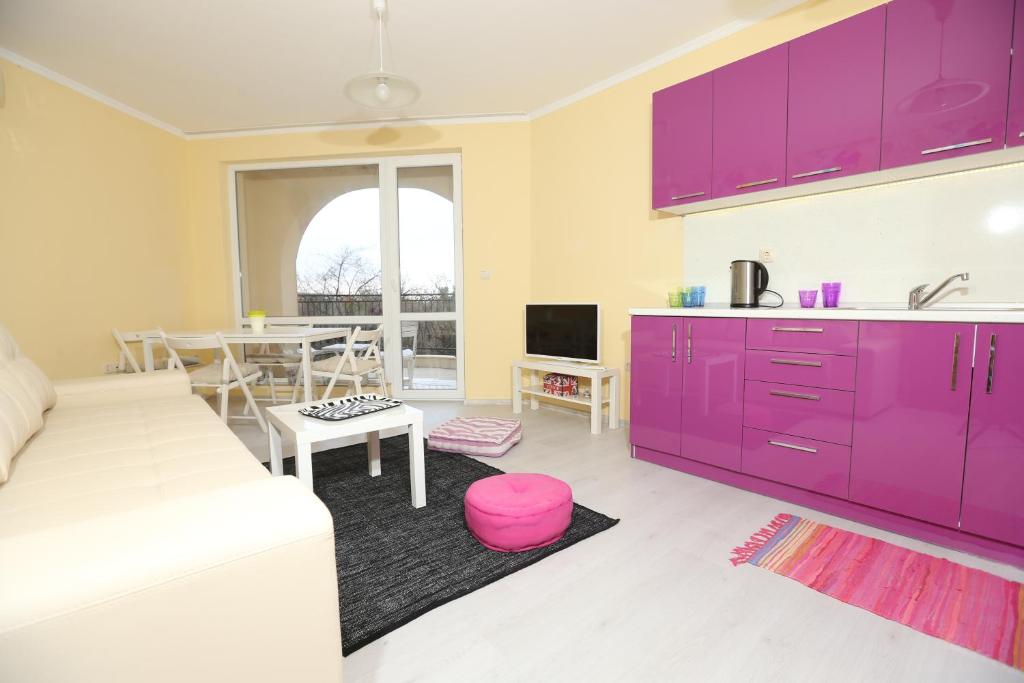 ein Wohnzimmer mit lilafarbenen Schränken und einem Tisch in der Unterkunft South Beach Apartments in Obsor