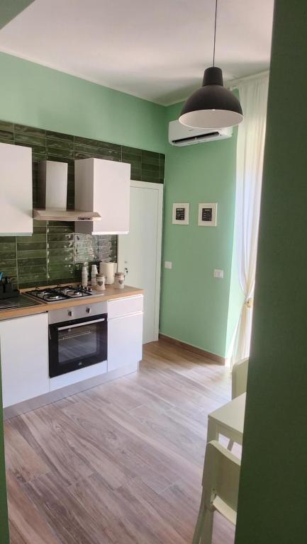 a kitchen with green walls and white cabinets at Casa Fraeli in Pozzuoli