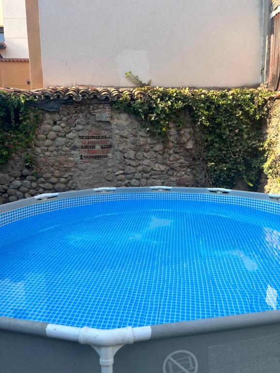 a blue swimming pool in front of a stone wall at La Posada De Alanah in Candeleda