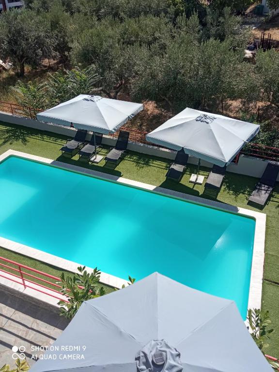 two umbrellas and a swimming pool with chairs and umbrellas at Melia Luxury Suite with pool in Iraklitsa