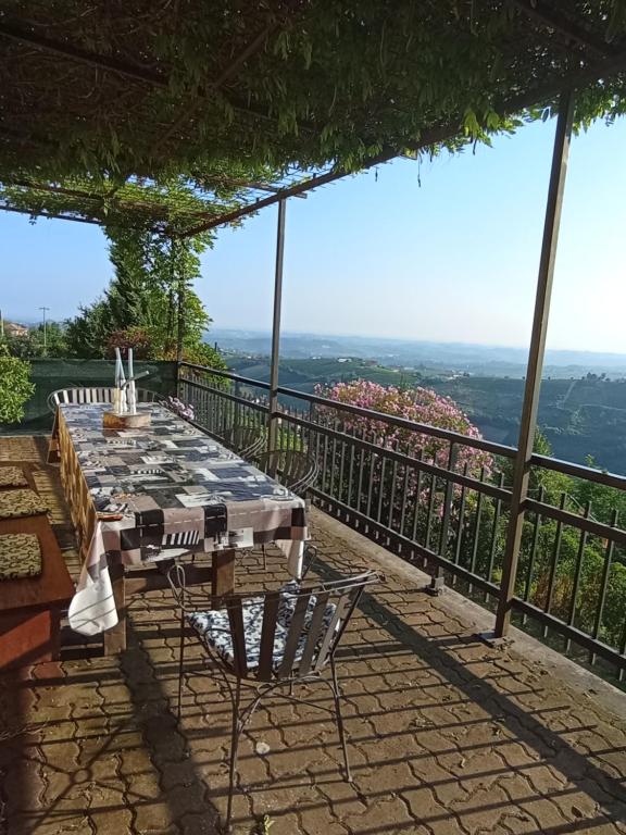 einen Tisch und Stühle auf einer Terrasse mit Aussicht in der Unterkunft Casa vacanza il colle del vento in Calosso