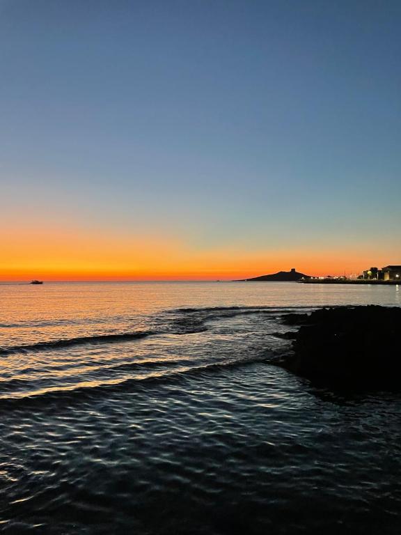 a beach with the sun setting in the ocean at Casa Chiara in Isola delle Femmine