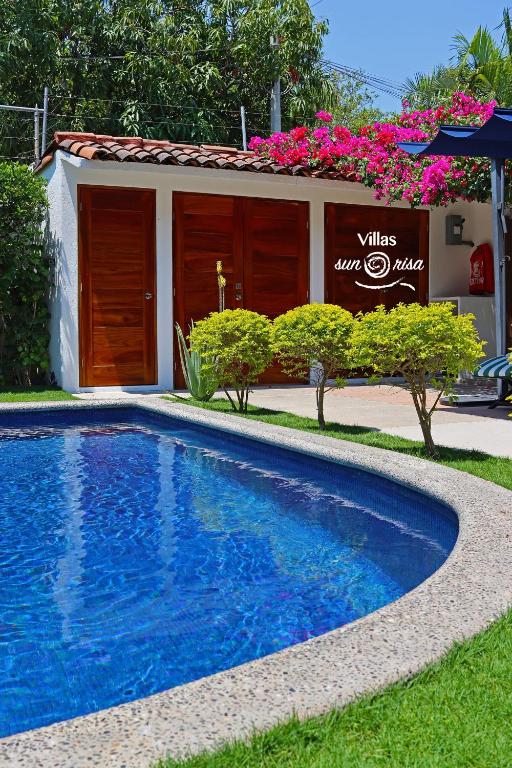 ein blauer Swimmingpool vor einem Gebäude in der Unterkunft Villas Sunrisa in Zihuatanejo