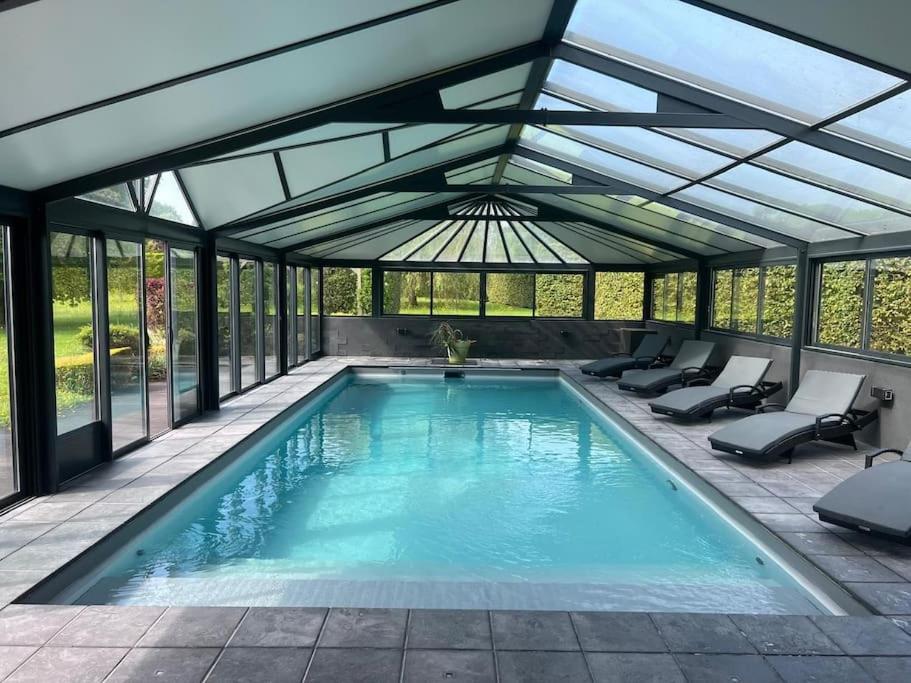 une piscine intérieure avec une véranda aux parois de verre dans l'établissement Villa Les Jardins de Parfondeval, à Parfondeval