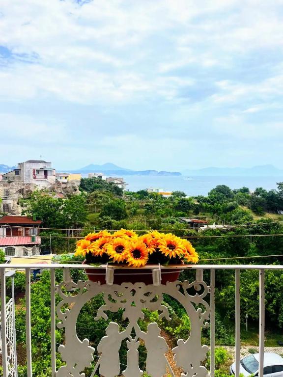 a vase filled with yellow flowers on a balcony at Casa Nina-Bacoli Elegant & View in Bacoli