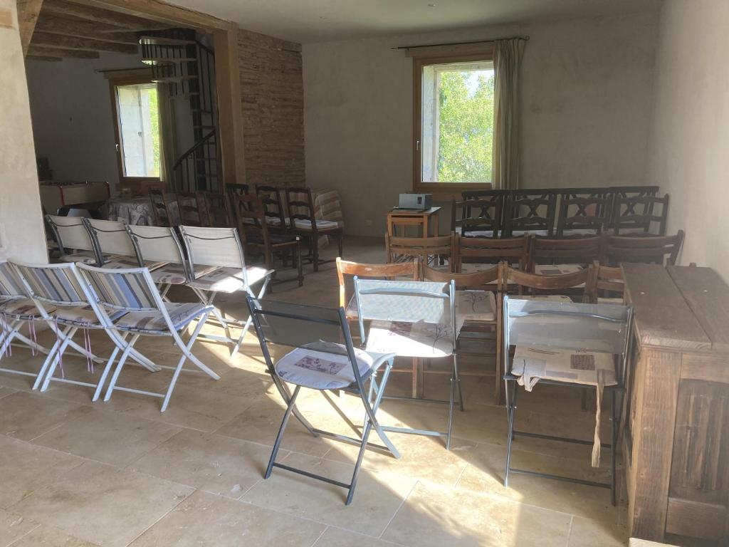 a room with chairs and tables and a table and windows at Domaine de la Salamandre in Auriac-du-Périgord