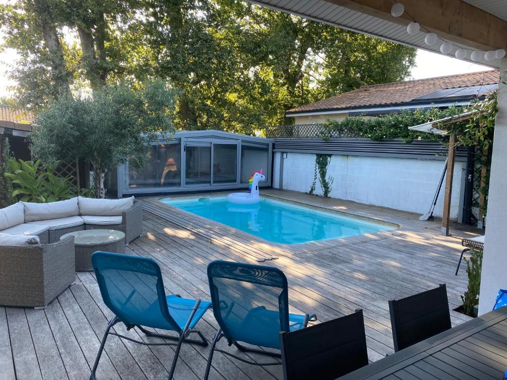 une terrasse avec une piscine, 2 chaises et un canapé dans l'établissement Cosy Villa Arcachon Bay, à Audenge