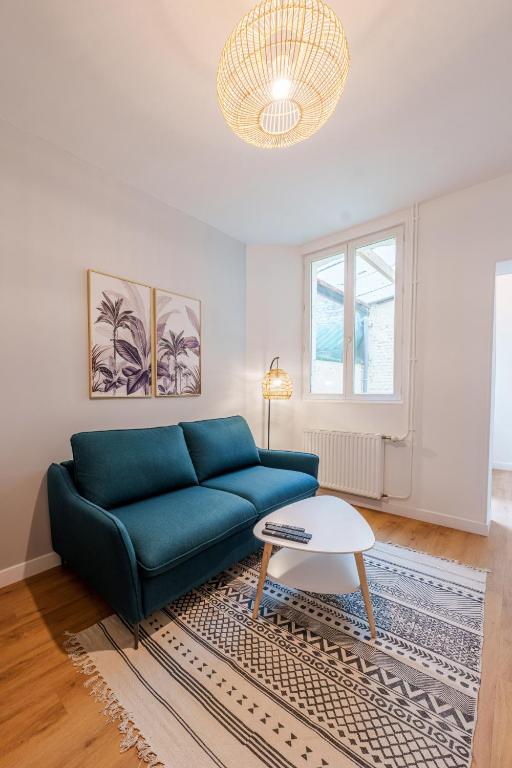 un salon avec un canapé bleu et une table dans l'établissement Appartement cosy proche de la gare, à Saint-Quentin