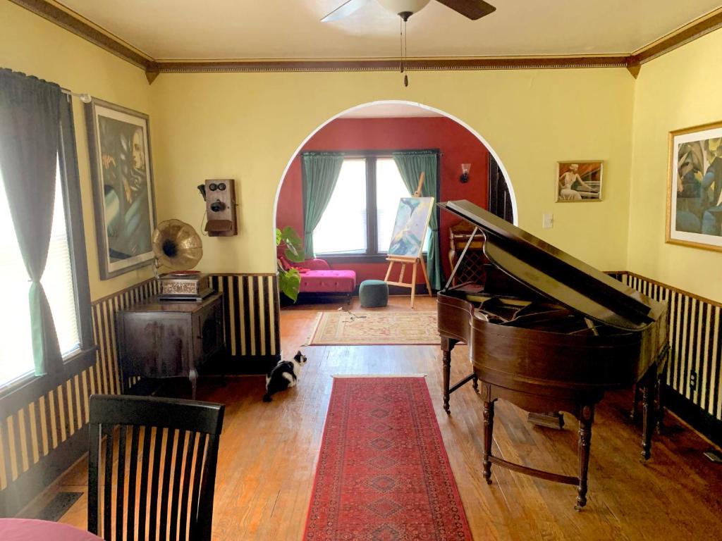 a living room with a piano and a cat sitting on the floor at Dr. Yaple's Art Deco House in Lafayette