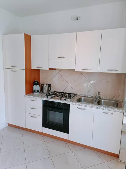 a kitchen with white cabinets and a stove and sink at Aeroporto & Fiera 30 in Seriate