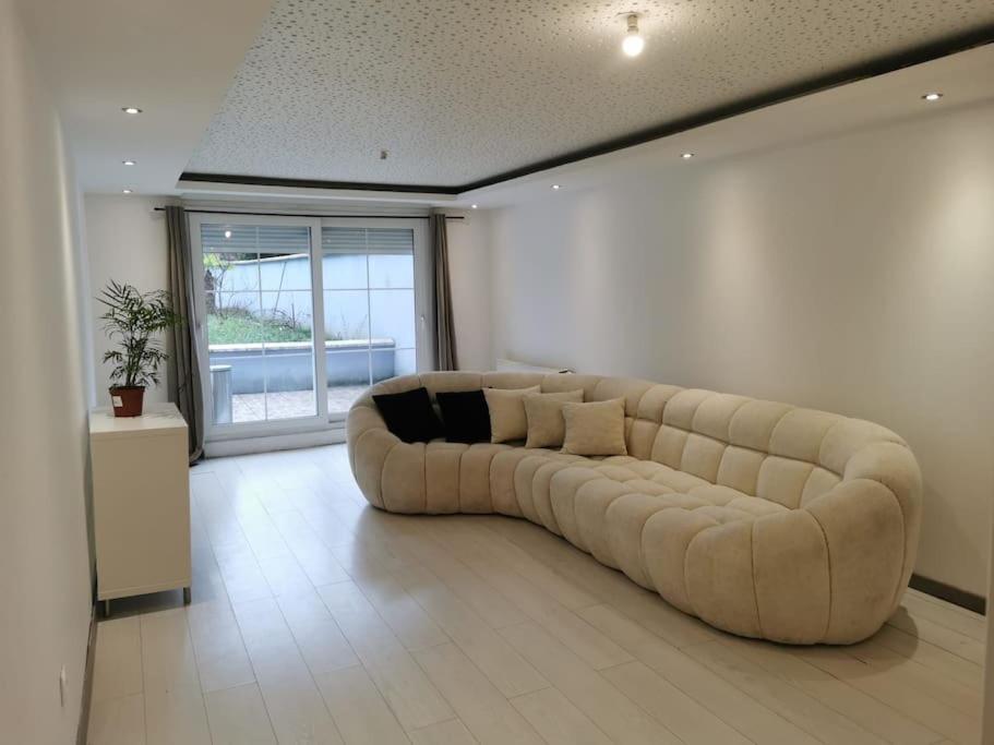 - un grand canapé blanc dans une chambre avec fenêtre dans l'établissement Centre-ville Sevran f3, à Sevran