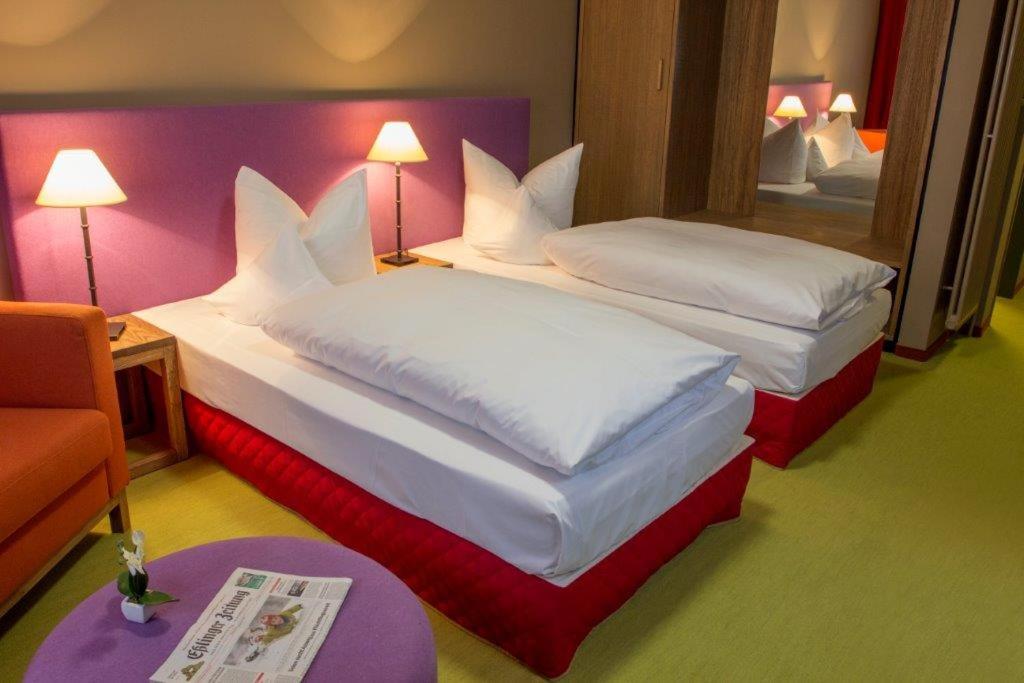 プロッヒンゲンにあるSchurwald Hotelのベッド2台と鏡が備わるホテルルームです。