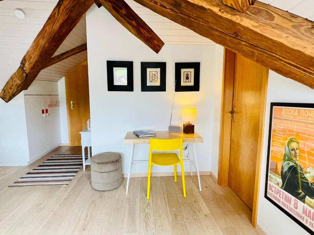 a yellow desk in a room with white walls and wooden beams at Beautiful One Bedroom Atelier Near City Lucerne in Ruswil