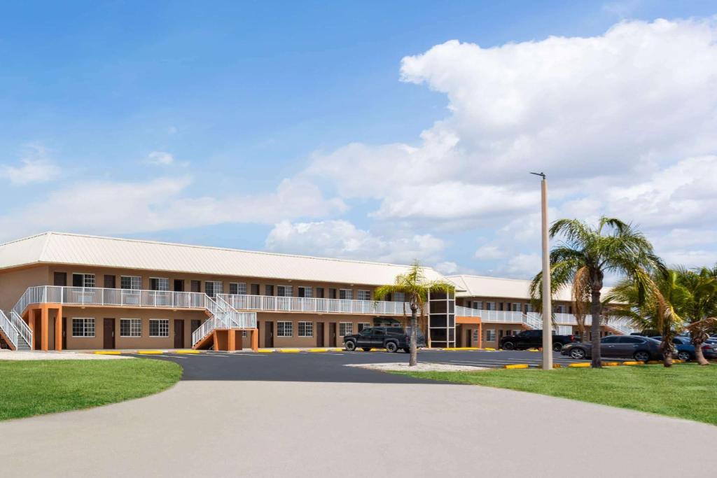 Un gran edificio con palmeras delante. en Travelodge Suites by Wyndham Lake Okeechobee, en Okeechobee