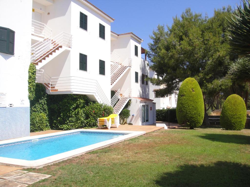 una villa con piscina di fronte a un edificio di Apartamentos Piscis a Cala Blanca