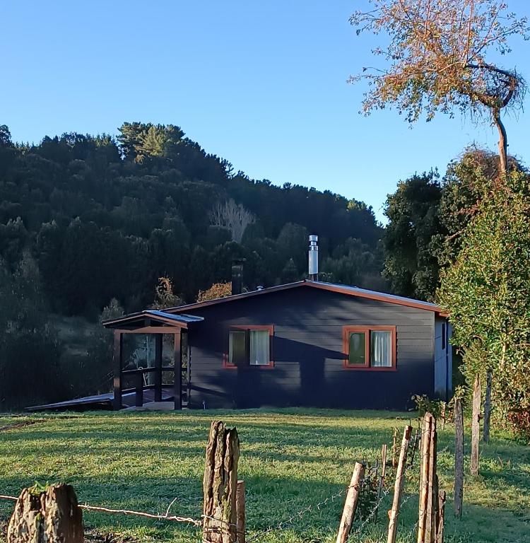 a house in a field with a fence at Cabaña VerdeNativo-Puerto Octay in Puerto Octay