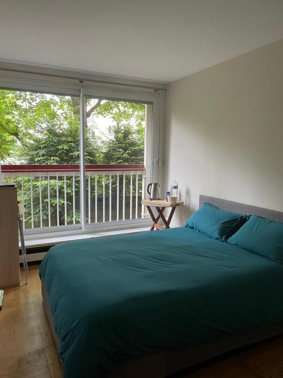 une chambre avec un grand lit et une grande fenêtre dans l'établissement Petit studio tout équipé, à Boulogne-Billancourt