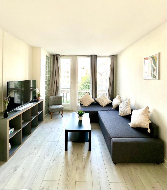 un salon avec un canapé et une télévision dans l'établissement Appart ensoleillé à Boulogne Billancourt, à Boulogne-Billancourt