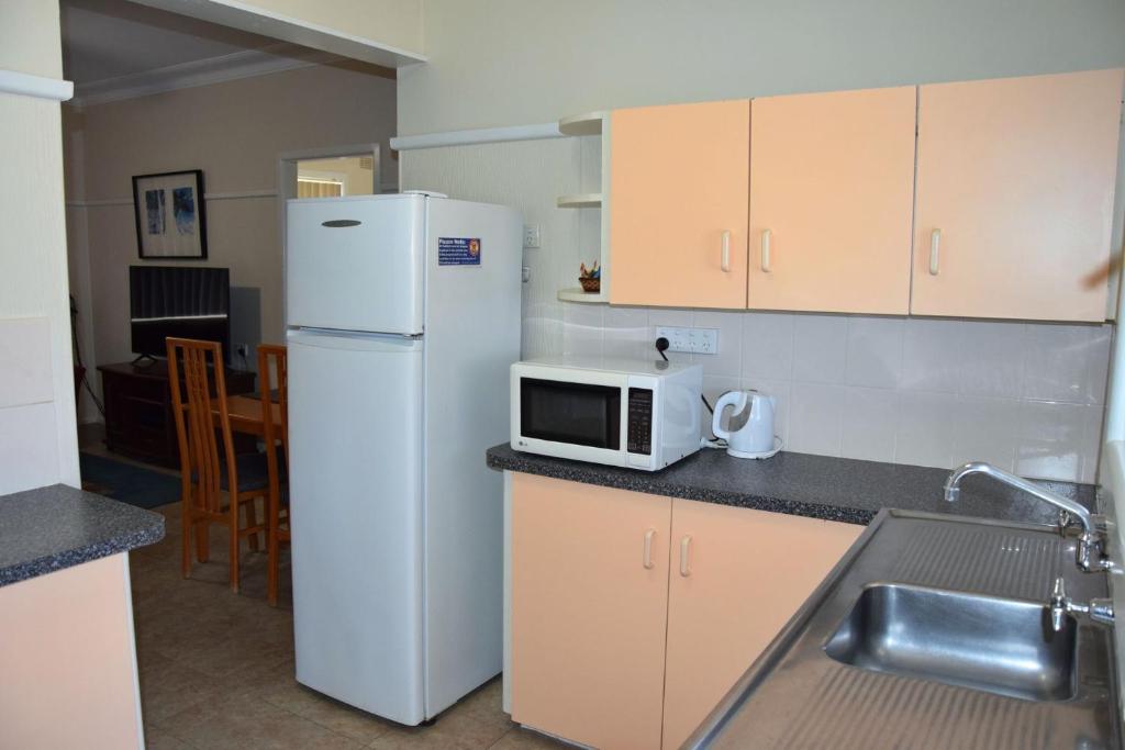 Una cocina con un refrigerador blanco y un microondas. en Clarkes Flat 3, en South West Rocks