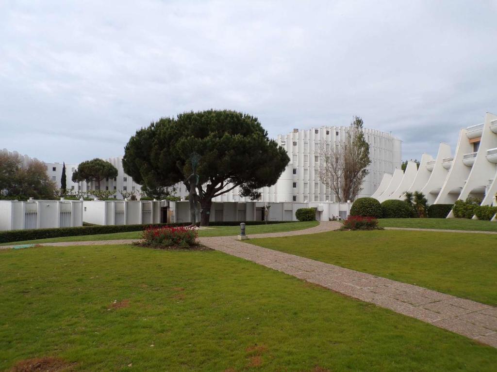 un parc avec un arbre et un bâtiment dans l'établissement Studio Coquet Proche Plage et Commerces, Terrasse, Parking, Clim, Wifi, Lave-Linge, Lave-Vaisselle - FR-1-328-221, à La Grande Motte