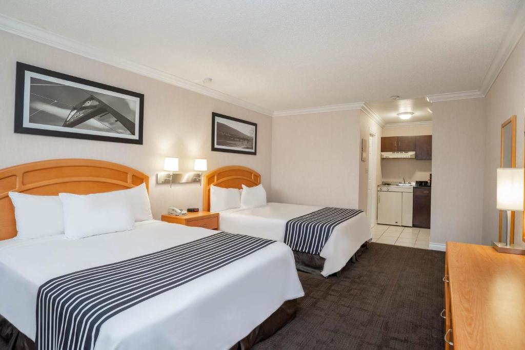 a hotel room with two beds and a kitchen at Sandman Hotel Revelstoke in Revelstoke