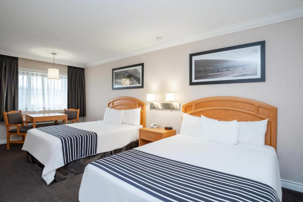 a hotel room with two beds and a desk at Sandman Hotel Revelstoke in Revelstoke