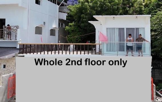 dos personas de pie en el balcón de una casa blanca en Laag Beach House, en Boljoon