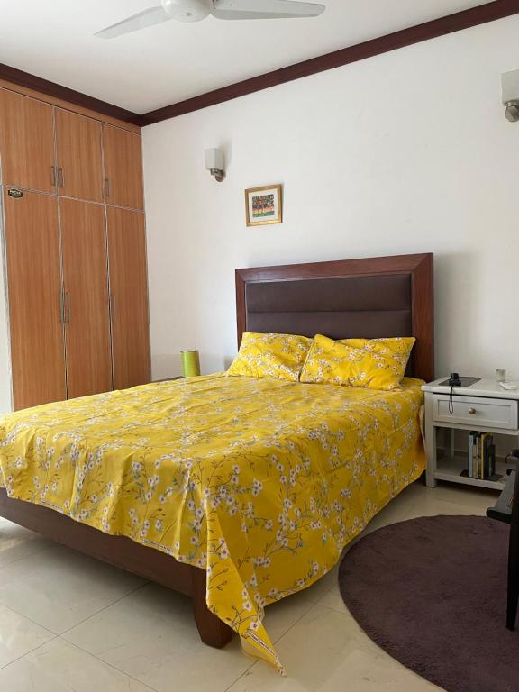 a bedroom with a bed with a yellow comforter at Townhouse Room in a Quiet Neighborhood in Rāmkot
