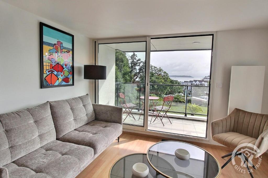 un salon avec un canapé et une table en verre dans l'établissement Face a tome, à Perros-Guirec