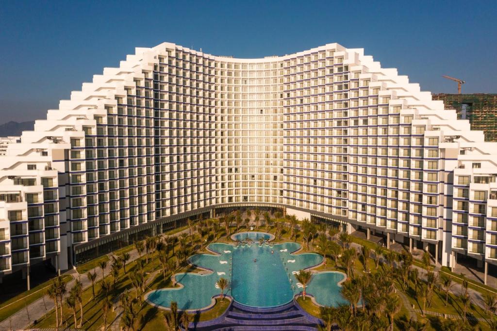 un grand bâtiment avec une piscine devant dans l'établissement Condotel Arena Beach Near the Airport, à Thôn Hòa Ða