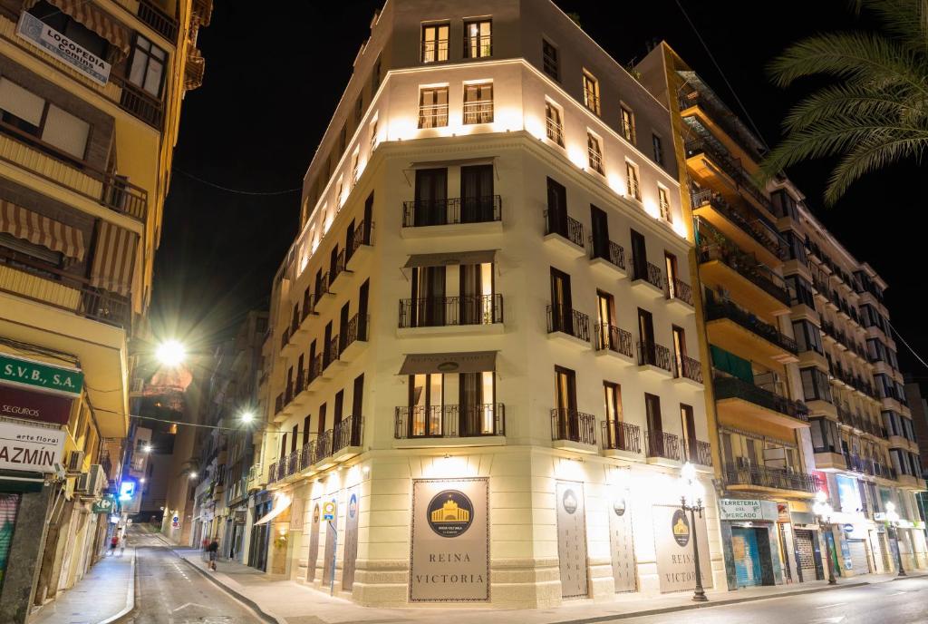a tall white building on a city street at night at Reina Victoria El Mercado in Alicante
