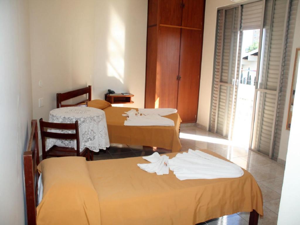 a room with three beds and a table and chairs at Scala Hotel Barretos in Barretos