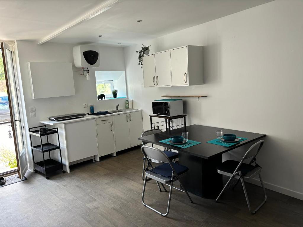 a kitchen with a table and chairs in a room at Gîte du bois des Genièvres in Amillis
