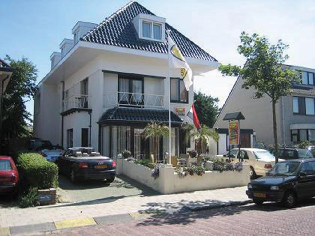 een groot wit gebouw met auto's geparkeerd voor het bij Hotel / Pension Villa Tanahlot in Zandvoort