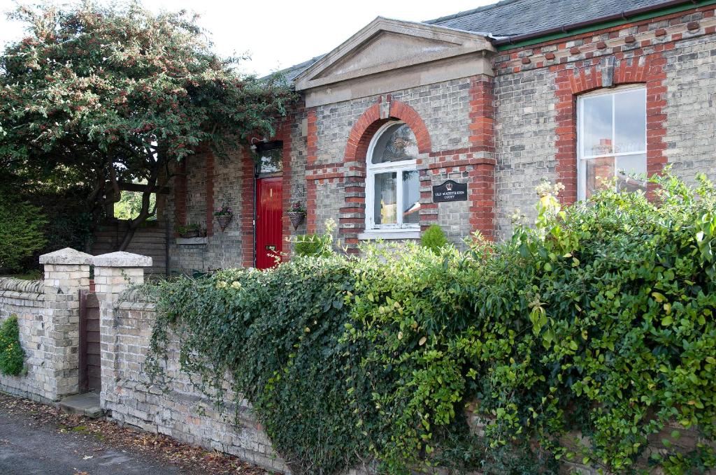 a brick house with a red door and a hedge at The Old Magistrates Court in Melbourn