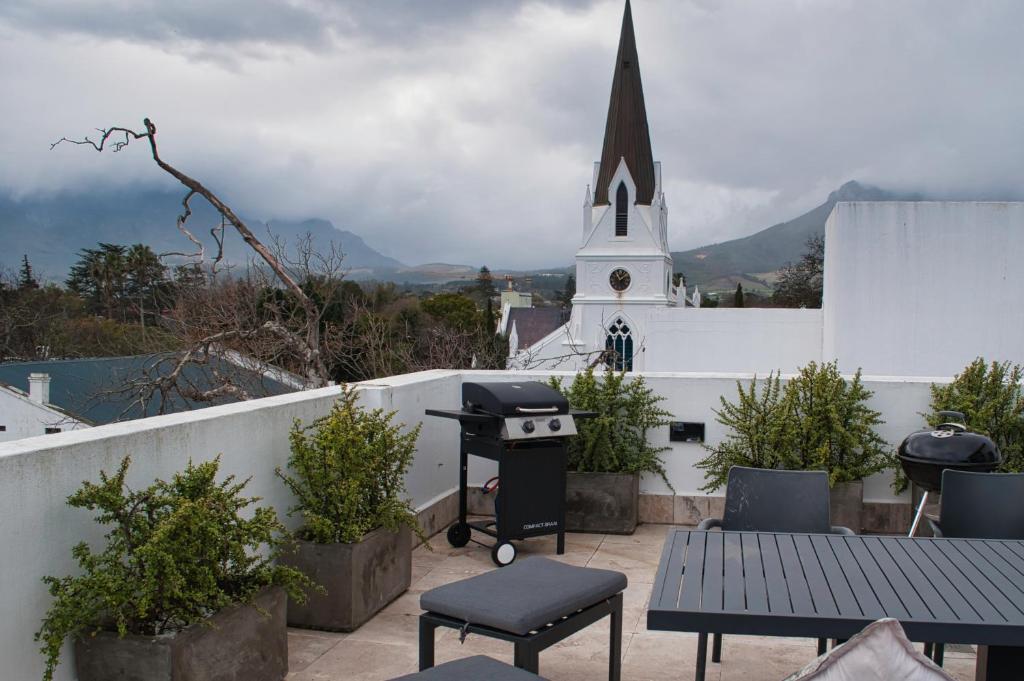 Un balcón con parrilla y una iglesia. en Stellenbosch Upper Class Penthouse, en Stellenbosch