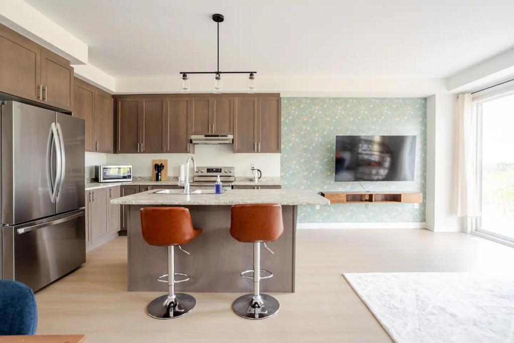 une cuisine avec un grand îlot et deux tabourets de bar dans l'établissement Stylish 4br Fast Wifi Sleeps 10, à Barrie
