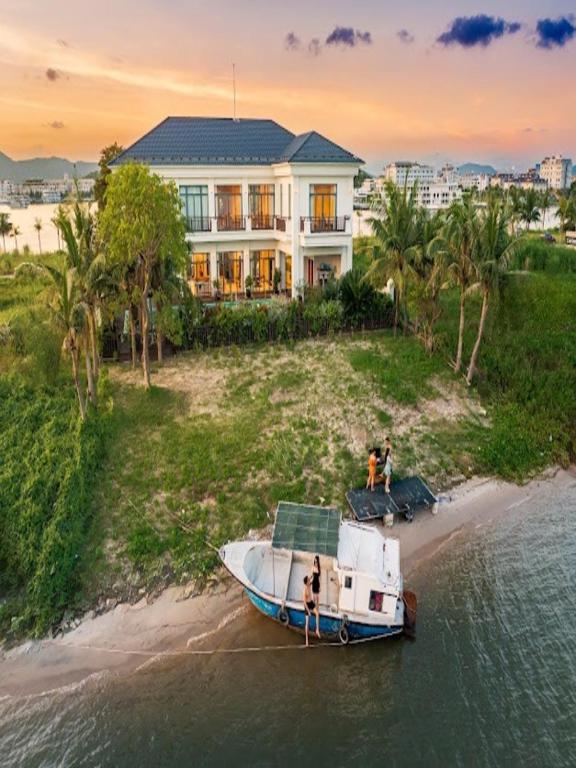 un bateau amarré sur la plage devant une maison dans l'établissement Villa 5 phòng ngủ víp - Tuần Châu - Sát biển, à Hạ Long