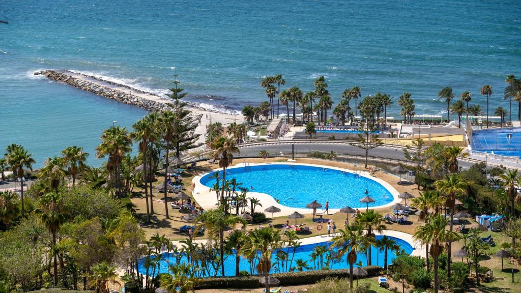 ベナルマデナにあるApartamento en Benalmádena - Colosoのリゾートのスイミングプールと海の空中を望めます。