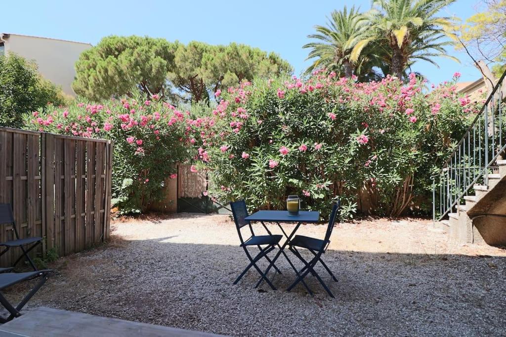 une table et des chaises dans une cour ornée de fleurs roses dans l'établissement T2 jardin, 100m de la plage, à Sanary-sur-Mer