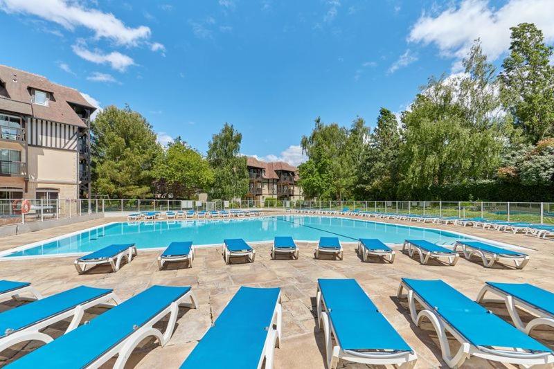 une piscine avec des chaises longues bleues et une piscine dans l'établissement Appartement 2 pièces, Rez de jardin et terrasse, à Deauville