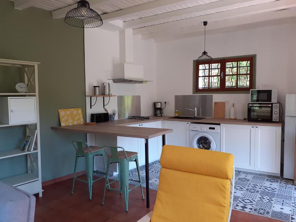 une cuisine avec une table et des chaises dans une pièce dans l'établissement Le Mardaris, à Reilhanette