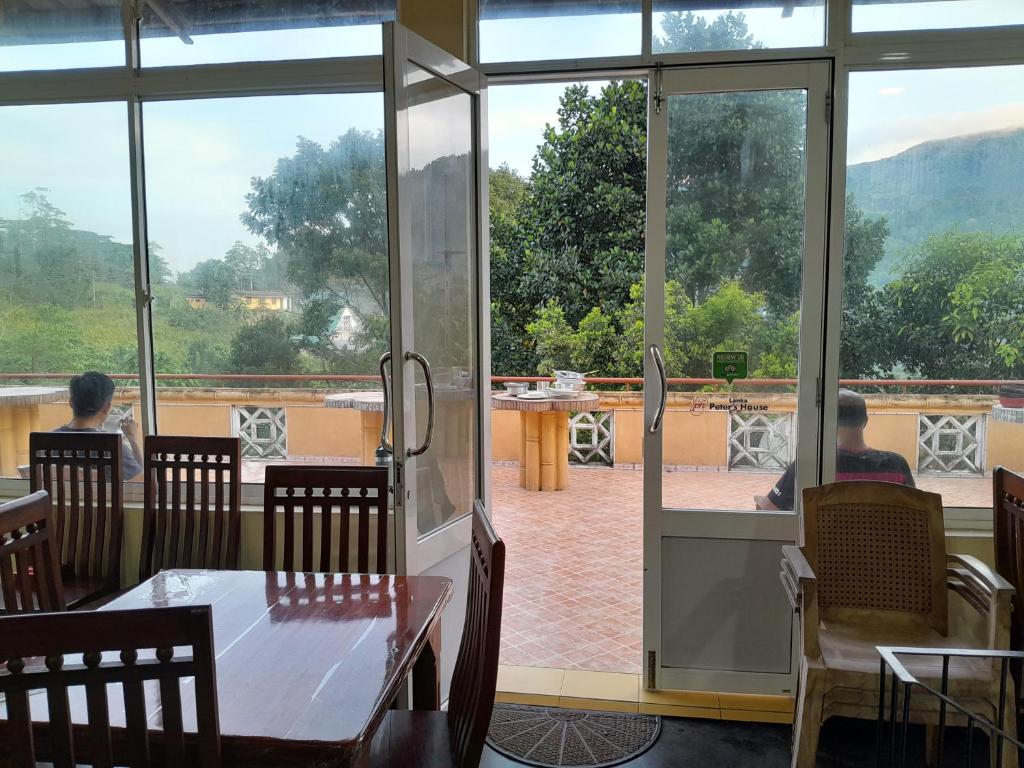 two people sitting at a table in a restaurant looking out the window at Lanka Peter's House in Peradeniya