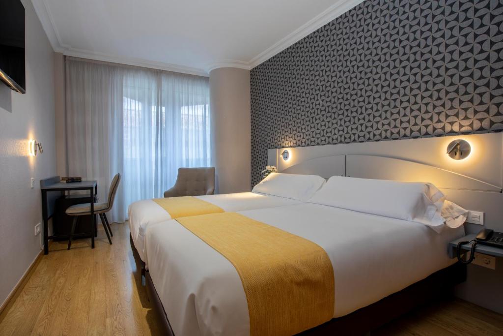 ein Hotelzimmer mit einem großen Bett und einem Schreibtisch in der Unterkunft Hotel Corona de Castilla Burgos in Burgos
