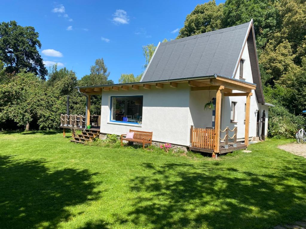 a small white house with a porch on a lawn at Ferienhaus zum Sonnenblick in Kröpelin