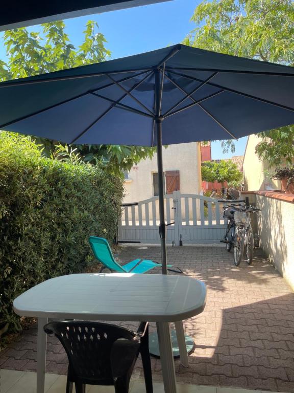 - une table et des chaises sous un parasol sur la terrasse dans l'établissement Belle maison T2 Mezzanine, au Barcarès