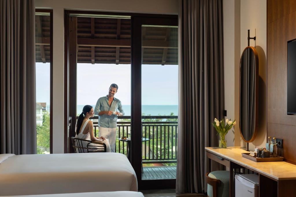 a man and a woman standing on a balcony in a hotel room at Holiday Inn Resort Bali Canggu by IHG in Canggu
