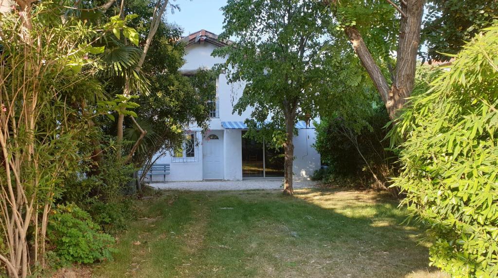 une maison blanche avec des arbres devant dans l'établissement LA PETITE BICOQUE au fond du jardin, à Quillan