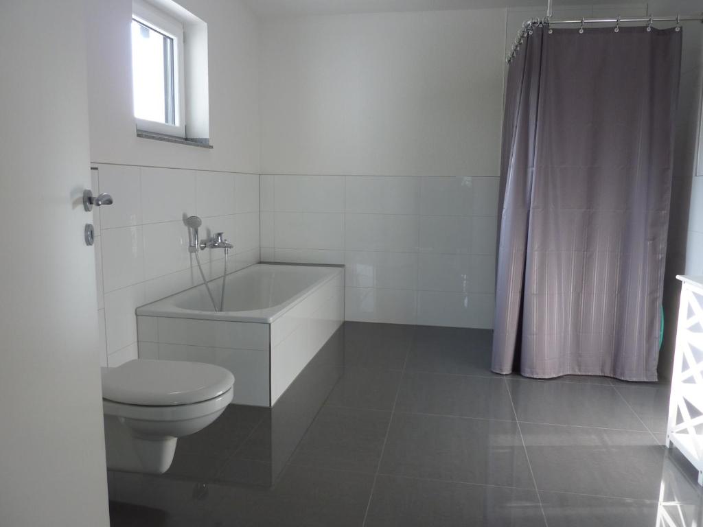 a white bathroom with a toilet and a sink at Barrierefreie Ferienwohnung in Erkelenz